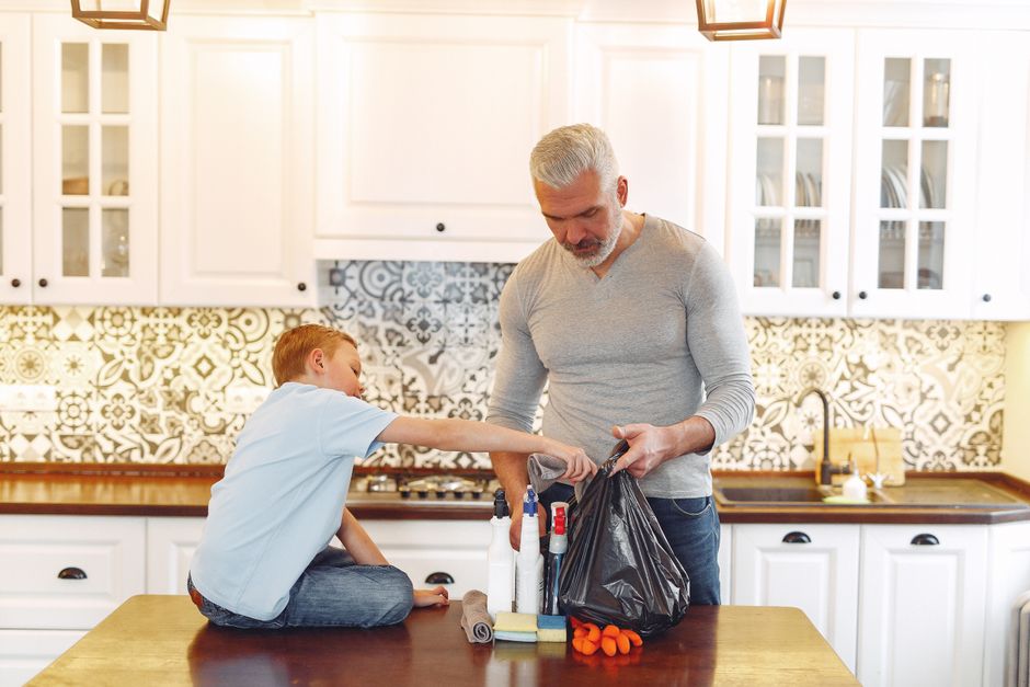 Grey haired dad with beard and small kid preparing cleaning stuff for tidying up kitchen